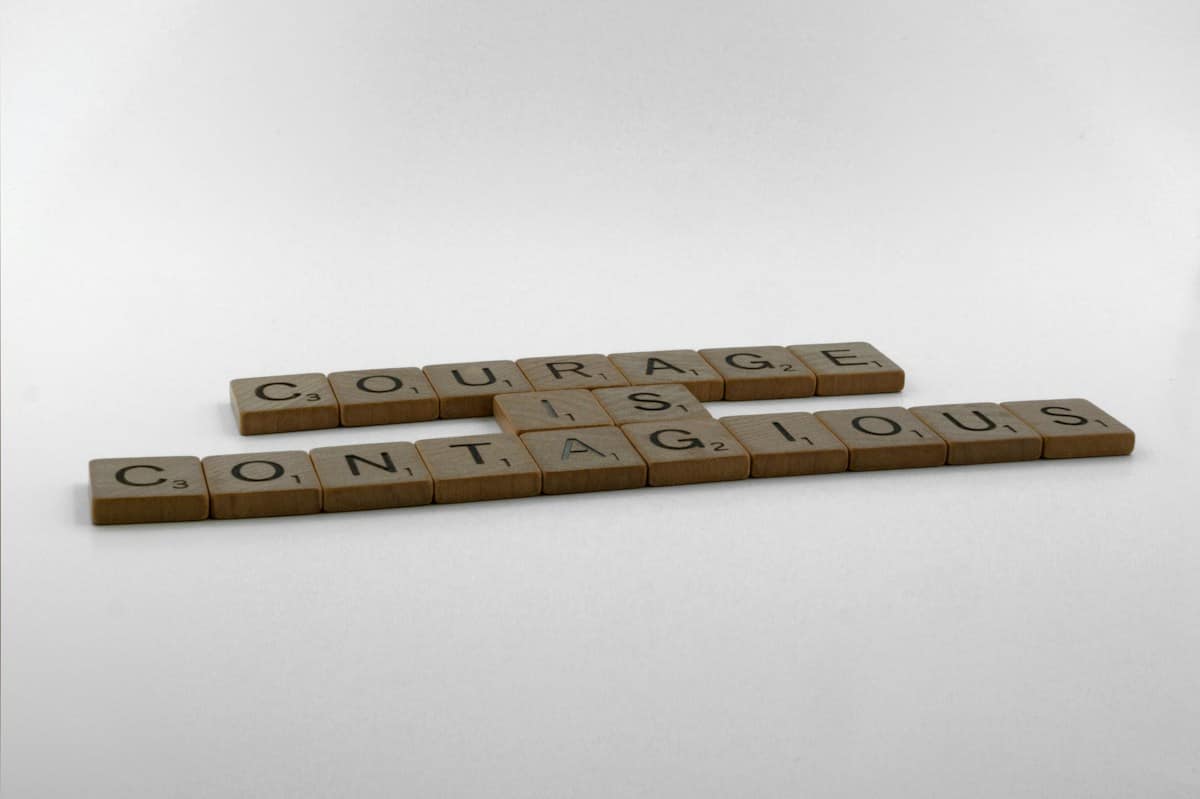 three scrabble tiles spelling out the word courageous